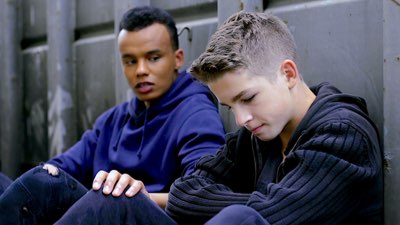 A teenage boy comforts his friend, who is looking sad.