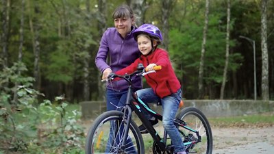 A mother helping her son learn to ride a bicycle