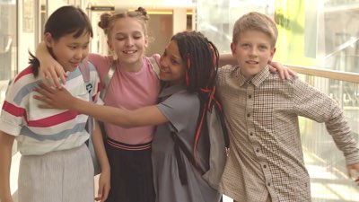 Three girls and a boy hugging in friendship