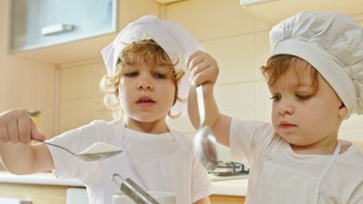 Two young boys dressed as chefs cooking together